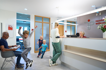 Kinder und Erwachsene im Wartebereich und Flur der Physiotherapie Praxis in Paderborn.