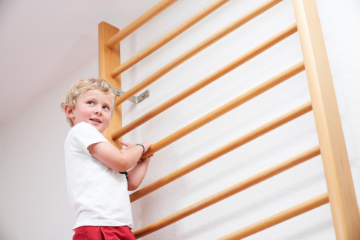 Kind klettert auf Sprossenwand in einer Physiopraxis in Paderborn.