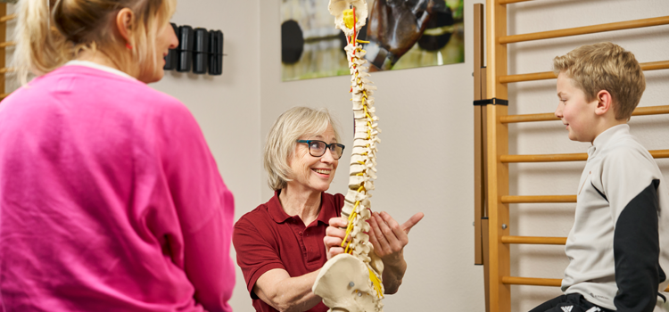 Anamnese für die Skoliose Therapie. Beratung der Therapeutin mit Mutter und Kind.