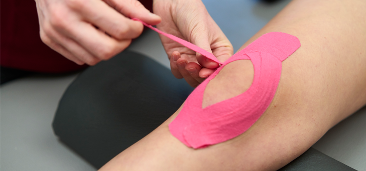 Physiotherapeut verwendet Kinesio Tape zur Stabilisation und Schmerzlinderung